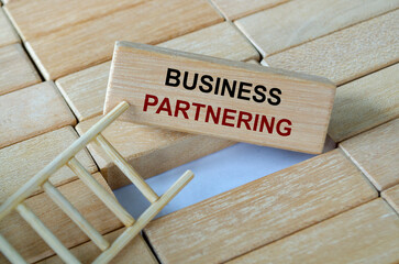 Business partnering text written on wooden blocks arranged on a ladder depicting collaboration for mutual success.