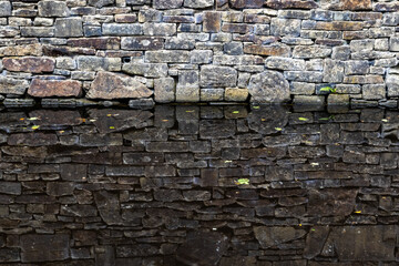 Weathered stone wall with its reflection mirrored in calm water