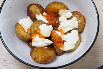 A bowl of roast potato with creme fraiche and salmon roe.