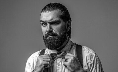 Gentleman his bowtie. Beard man in bow tie and suspenders. Male in shirt correcting his colorful tie. Black and white