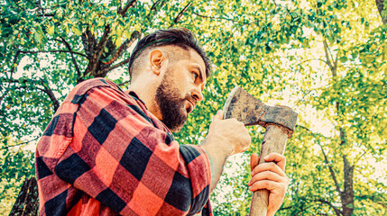 Bearded lumberjack with a large ax. Bearded guy in a summer forest an ax in his hand