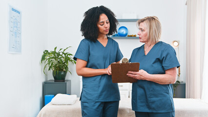 Physiotherapist Discussing Treatment Plan With Senior Mentor In Clinic During Therapy Session
