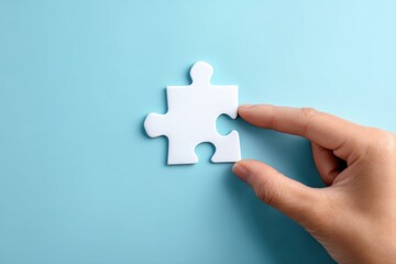 Hand placing a white jigsaw puzzle piece on a light blue surface