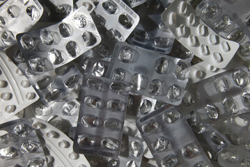 Empty blisters of pills, capsules, and medications. Symbol of finished treatment or drug overuse. Used pharmaceutical packaging. Close-up of medicine foil packaging.