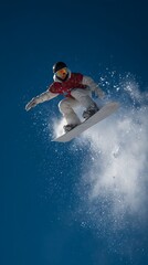 Snowboarder jumping through air with blue sky.