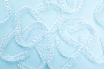 Invisible orthodontics cosmetic brackets on blue background. Tooth aligners, for beautiful smile. This invisible aligner showcases a modern approach to orthodontics and confidence in her appearance.