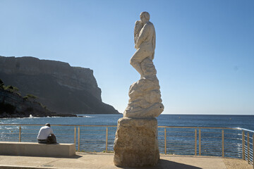 fisherman statue mounted on a stone pedestal near the water&rsquo;s edge in Cassis, Provence, France