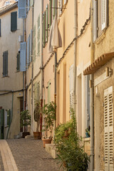 beige stone building with multiple shuttered windows. one window has clothes hanging on an outdoor drying rack, including dark-colored pants and shirts in Bandol, Provence, France
