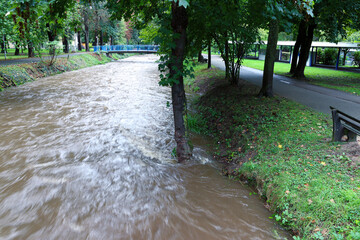 Flood waters flowing down the river after heavy rain with motion blur of the water (river Neumagen, Bad Krozingen, Germany)