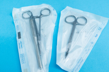 Sterile surgical instruments and medical tools sealed in individual packaging on a blue background