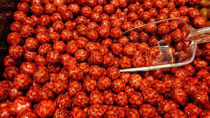 Pale yellow, almond-shaped chocolates are clustered together. They have a glossy surface,...