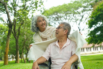 Fototapeta premium Happy Asian Senior Couple Relaxing Together in Park with Wheelchair