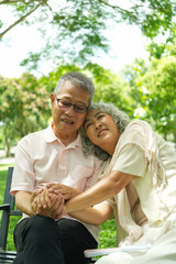 Fototapeta premium Happy Asian Senior Couple Relaxing Together in Park with Wheelchair
