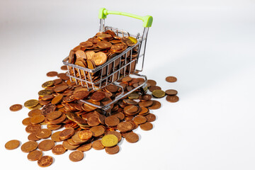 Mini shopping cart filled with euro cent coins, surrounded by scattered coins, symbolizing savings,...