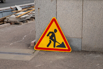 Construction sign placed on the bridge warns pedestrians of ongoing work in an urban area during daytime