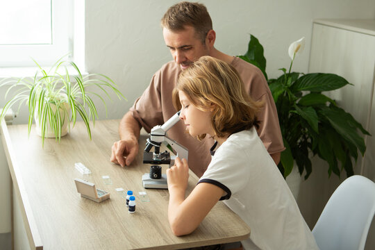 Father and daughter explore biology at home with a microscope, learning together about plants and science