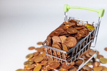 Mini shopping cart filled with euro cent coins, surrounded by scattered coins, symbolizing savings, budgeting, commerce, spending, and small financial value.