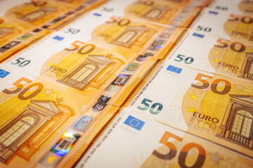 Close-up of multiple 50 euro banknotes spread out in rows, symbolizing wealth, finance, savings, investment, economy, and monetary value.
