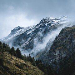 Atmospheric alpine landscape with snow-covered mountain top under snow gray sky
