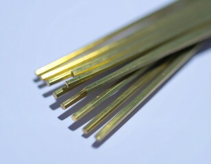 Close up of shiny hexagonal brass rods on light blue surface