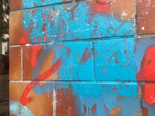 Close-up of urban graffiti on textured brick Berlin wall orange blue teal red