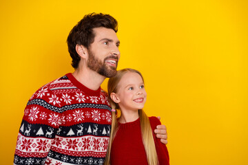 Happy father and daughter enjoying holiday bonding in colorful sweaters against vibrant yellow...
