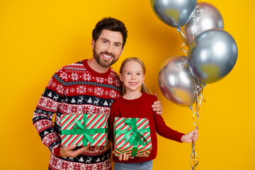 Dad and daughter celebrating Christmas together, holding gifts and balloons against a festive...