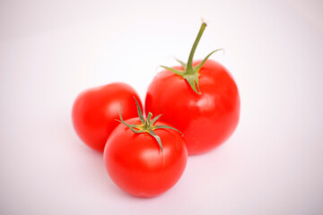 Three ripe red tomatoes on a white background.