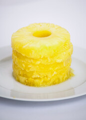 Stack of pineapple slices on a white plate