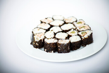 Sushi rolls arranged on a white plate against a clean, white background.