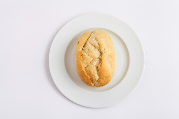 Bread roll on a white plate against a white background.