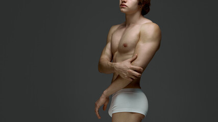 Male model in white underwear crossing arms with reflective pose. Concept of male anatomy, wellness...