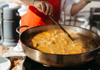 Close-up of traditional rabbit stew being stirred in large pot