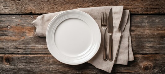 The elegant white plate set on a rustic wooden table with cutlery.
