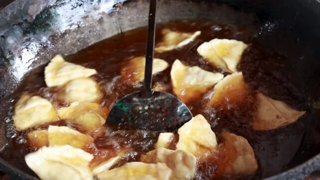 Samosas sizzle in a large kadai filled with unhealthy reused hot oil, a common practice in Indian street food. While delicious, using unhealthy oil raises health concerns.