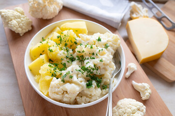 Cauliflower with a delicious gouda cheese sauce and boiled potatoes on a plate. Budget friendlich and easy to cook meal