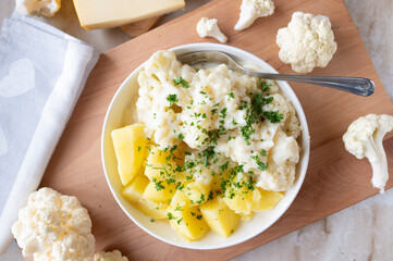 Cauliflower with a delicious gouda cheese sauce and boiled potatoes on a plate. Budget friendlich and easy to cook meal