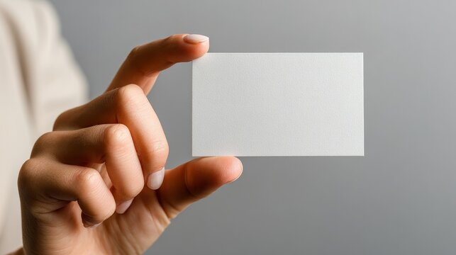 Presented here is a blank business card mockup held by a woman’s hand on a neutral backdrop, ideal for customization, marketing, branding, and promotional purposes, providing a professional look for