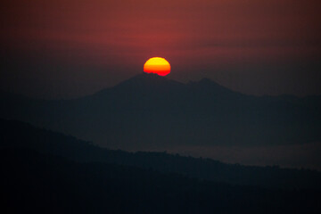 Obraz premium Fiery Sunset Over Mountain Silhouette
