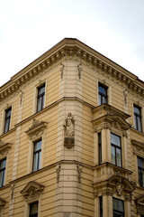 Historic building facade with ornate windows, sculpture, and decorative details against cloudy sky. Elegant architectural heritage symbolizing culture and history.