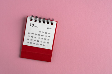Desktop calendar for October 2025 on a pink background, with copy space.