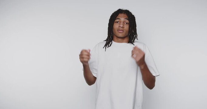 footage of young man with long hair wearing a white t-shirt strikes a casual pose, showcasing a confused expression on white background