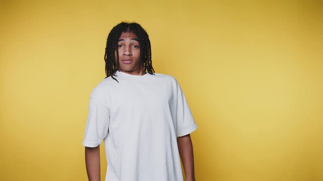 footage of young man displays a humorous yet sardonic smirk, creating a playful atmosphere on yellow background