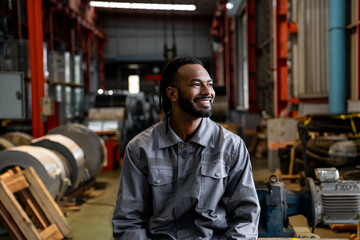 A man in a grey uniform is smiling in a factory