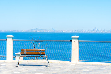 Scenic view of a bench overlooking the tranquil water and distant city skyline on a clear day