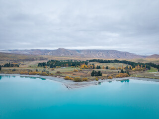beautiful turquoise lake with colorful autumn leave tree is beautiful land scape at lake tekapo South Island new zealand