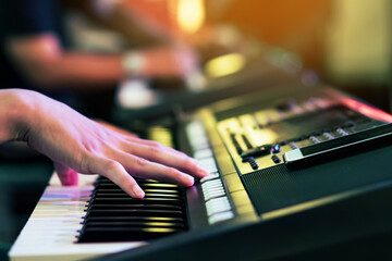Hands of male musician press digital electronic keyboard synthesizers on concert stage. Pianist man hands play the keys of electronic piano. Piano music pianist hand playing. Selective focus on hand.