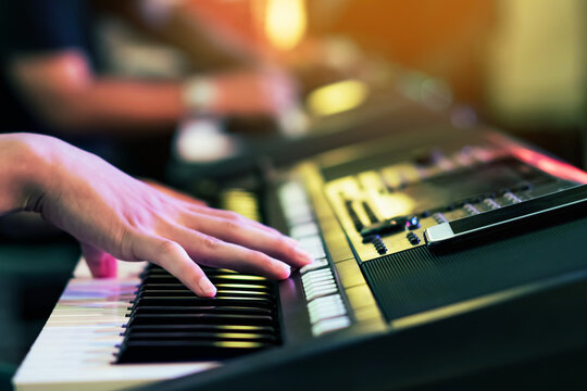 Hands of male musician press digital electronic keyboard synthesizers on concert stage. Pianist man hands play the keys of electronic piano. Piano music pianist hand playing. Selective focus on hand.