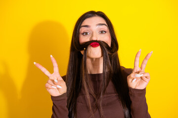 Fototapeta premium Charming brunette woman playfully posing with a vibrant expression against a bright yellow background