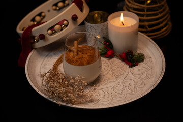 Rompope with cinnamon sticks, burning candle, and tambourine celebrating christmas festivities